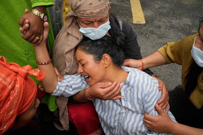 People helping a woman during flood response in Nepal